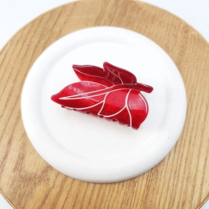 Macro detail of red leaf hair claw clip with marble texture and white vein patterns