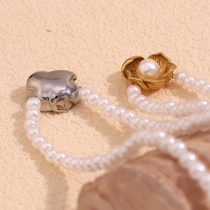 Detailed view of flower pendant necklaces with white pearls in gold and silver plating