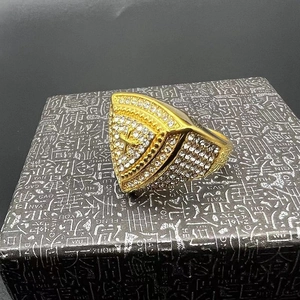 Macro shot of gold-plated hip hop ring with triangular cross design and inlaid rhinestones