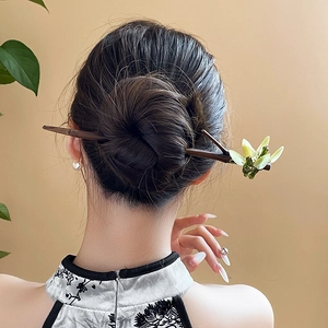 Detail of a Chinese style wooden hair pin with green flowers on a bun hairstyle