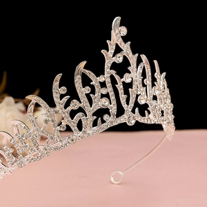 Detailed macro of silver tiara showing intricate vine patterns and clear rhinestones