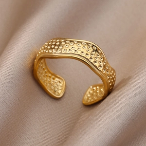 Detail of 18k gold plated stainless steel wave ring with hammered texture on silk fabric
