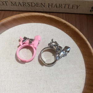Detail of adjustable puppy rings with bowknots and enamel finish in a rustic tray