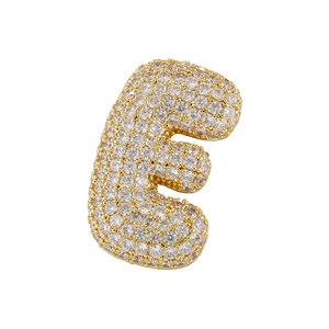 Close-up of golden letter E pendant with cubic zirconia stones and puffy texture