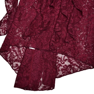 Detailed close-up of dark red lace fabric texture with irregular hemline on a summer gown