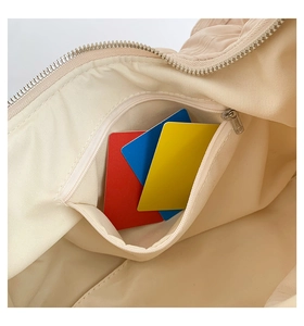 Detail view of the inner zipper pocket in a cream-colored pleated cloud tote bag