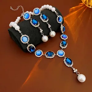 Luxury blue gemstone and pearl necklace with matching earrings on black velvet display