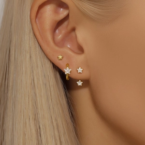 Detailed view of three-piece gold star earring set with white zircons on female model
