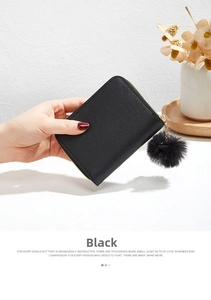 Detail of black faux leather mini purse with gold zipper and fluffy pompom keychain