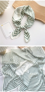 Detailed view of white silk scarf with green geometric lines and abstract face patterns