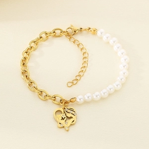 Detail of gold titanium bracelet featuring mother-child heart pendant and pearls