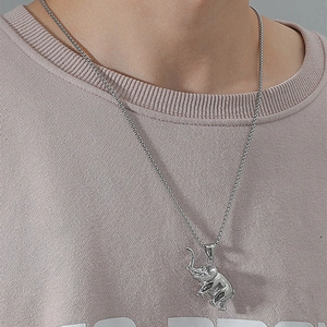 Detailed close-up of a silver elephant pendant on a necklace worn by a male model