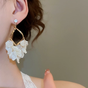 Close-up of elegant gold petal tassel earrings with shell texture on a female model
