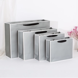 Modern grey paper gift bags with white piping and black rope handles in four sizes