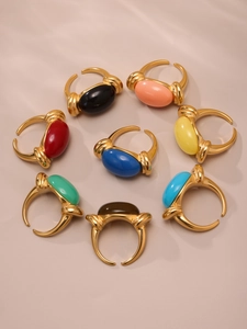Top view of eight gold adjustable rings with colorful oval resin stones in a circular layout