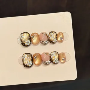 Handmade gold camellia press-on nails with 3D floral details and sparkling rhinestones