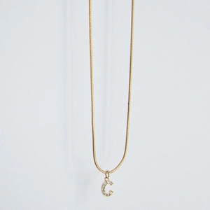 Detail of gold letter C pendant with sparkling zircons on a sleek snake chain