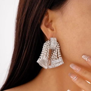 Close-up of sparkling silver tassel earrings with bow design on a female model