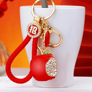 Detail of red apple keychain with braided rope, gold hook, and crystal accents