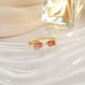 Detailed close-up of a gold open ring featuring pink rectangular gemstone settings