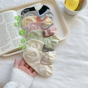 Pastel colored cotton no-show socks in grey black pink and beige on a cream tray