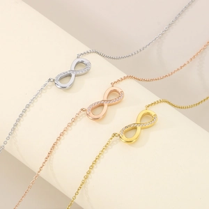 Three infinity charm bracelets in gold, silver, and rose gold with pavé cubic zirconia