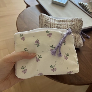 Detail of floral cotton coin purse with purple zipper pull and quilted fabric texture