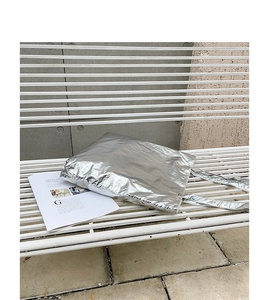 Chic silver metallic nylon tote bag with crinkled texture placed on white garden bench