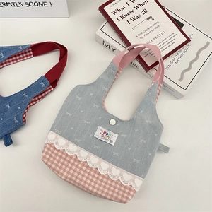 Detail of blue denim and pink plaid handbag with heart lace and bow print accents