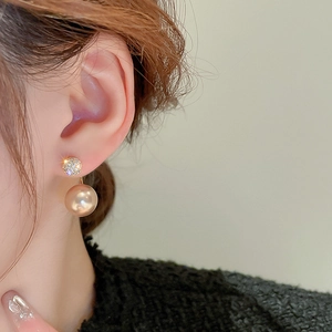 Close-up of elegant champagne gold stud earrings with cubic zirconia and faux pearls