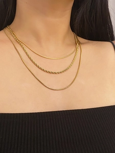 Close-up of layered 18K gold plated snake and twisted chain necklace on a model