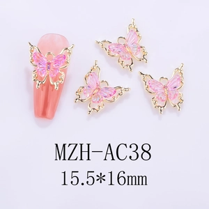 Detailed view of pink iridescent butterfly nail charms with gold frames on white background