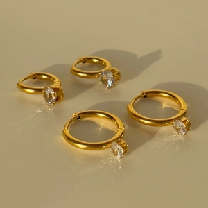 Detailed view of four 18k gold plated titanium steel hoop earrings with round zircon pendants