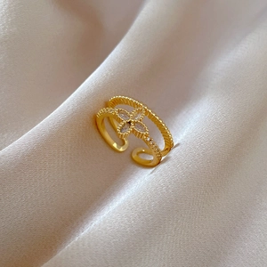 Detail of gold double-layered open ring with clover shaped zircon on silk fabric