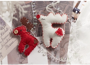 Detail of wool felt reindeer ornaments in red and white colors on a festive background