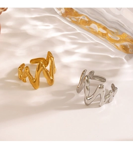 Detail of irregular wave rings in gold and silver with a liquid lava metal texture