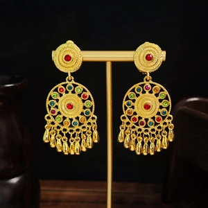 Bohemian gold drop earrings with colorful crystals and fringe on a display stand