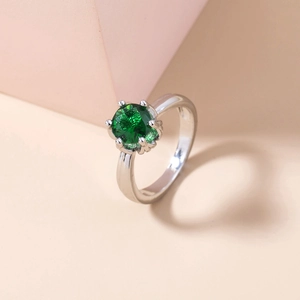 Detailed close-up of a silver ring featuring a round green gemstone in a classic claw setting