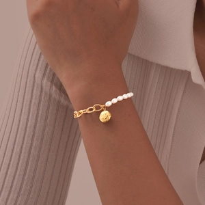 Detail of a vintage-style gold stainless steel smile pendant with pearl bead chain