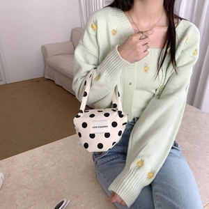Close-up of canvas polka dot handbag with logo patch paired with floral knit cardigan