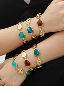 Detail of 18k gold plated bracelets with teardrop resin stones in red, green and blue