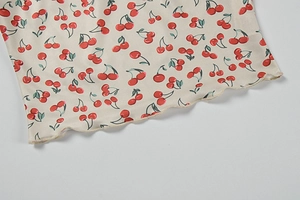 Close-up of cherry floral print fabric on white camisole with ruffled lettuce hem