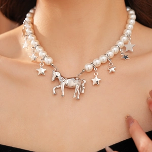Close-up of pearl necklace with silver pony pendant and shiny star charms on the neck