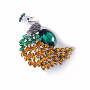 Detail of peacock brooch featuring emerald crystal and gradient rhinestone tail feathers