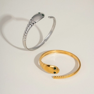 Detail of snake open bangle with green gemstone eyes in gold and silver finish