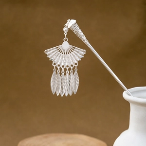 Detailed view of silver hollowed fan hair stick with leaf tassels in a ceramic vase