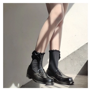 Detail showing black cotton mid-calf socks with lace trim and grey bow on loafers