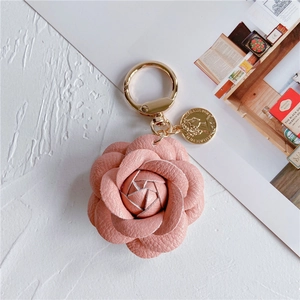 Detail of pink leather camellia keychain with golden spring clip and coin pendant