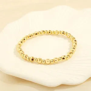 Close-up of golden beaded stretch bracelet with polished and faceted beads on shell tray