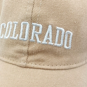 Detailed close-up of white Colorado letter embroidery on khaki cotton baseball cap